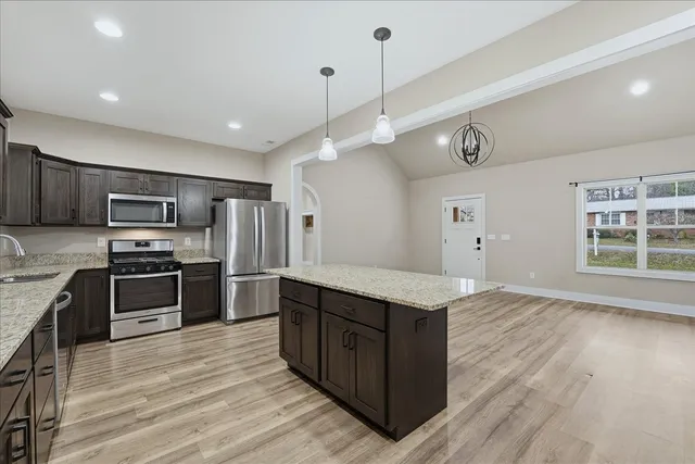 a kitchen with stainless steel appliances granite countertop a sink a stove and a refrigerator