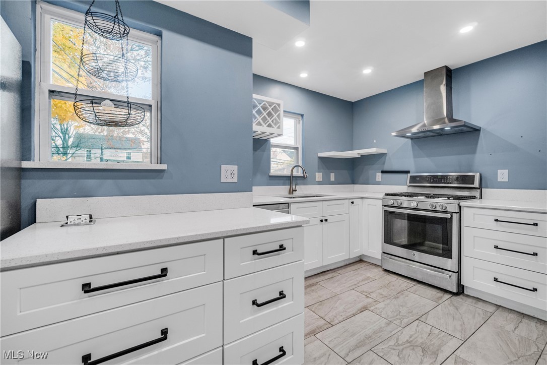 4430 Silsby Road Cleveland, OH 44118 - Photo 20 of 43 Kitchen with sink, wall chimney exhaust hood, stainless steel gas range oven, pendant lighting, and white cabinets