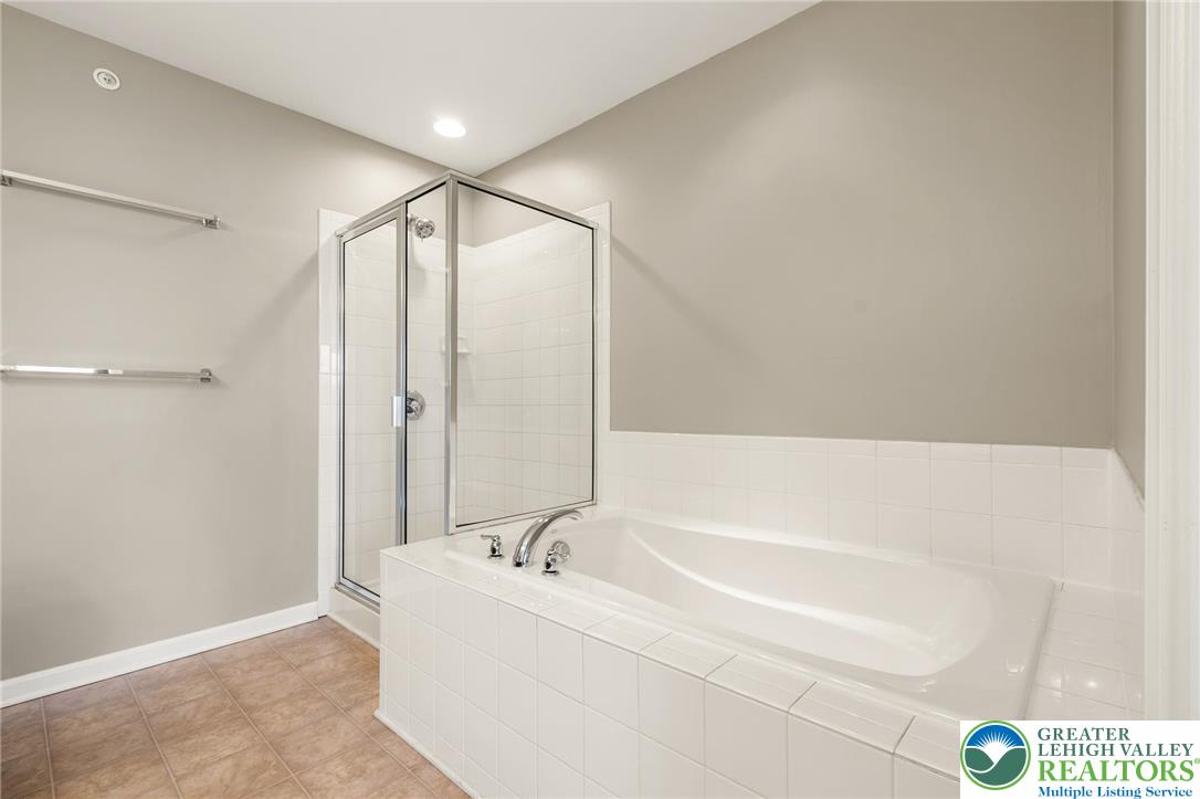8455 Starling Road Breinigsville, PA 18031 - Photo 15 of 24 Tiled flooring complements a separate glass-enclosed shower and a deep soaking tub in this primary bathroom.