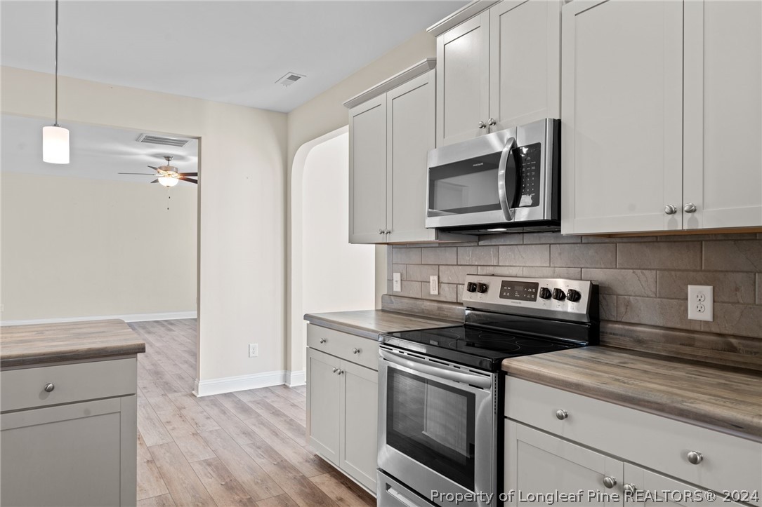 560 Angel Oak Drive Bunnlevel, NC 28323 - Photo 22 of 49 a kitchen with stainless steel appliances granite countertop a stove a microwave and a white cabinets