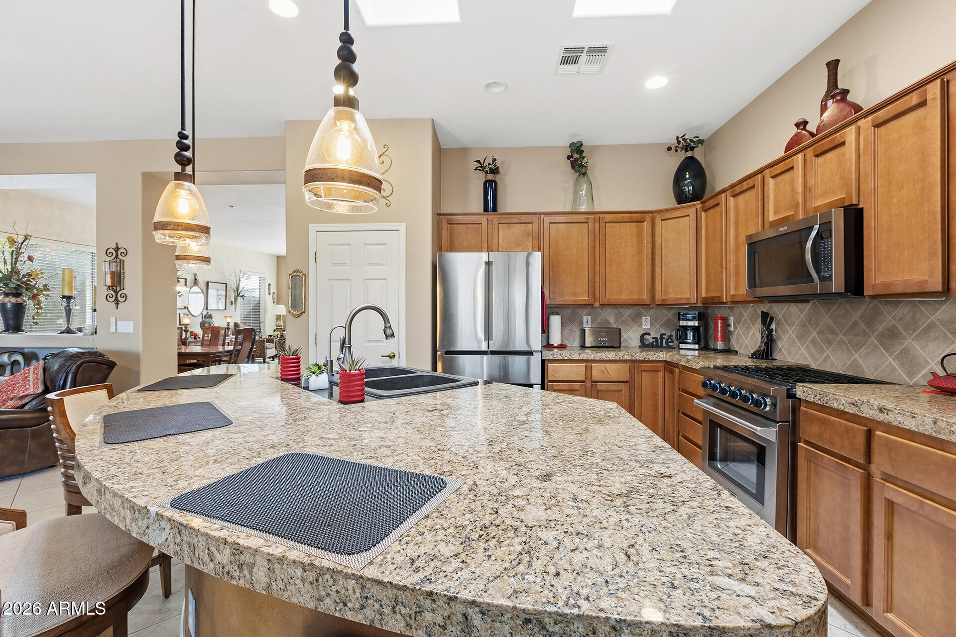 41712 North Golf Crest Road Anthem, AZ 85086 - Photo 18 of 39 a kitchen with stainless steel appliances granite countertop a stove top oven a sink a refrigerator white cabinets and wooden floor