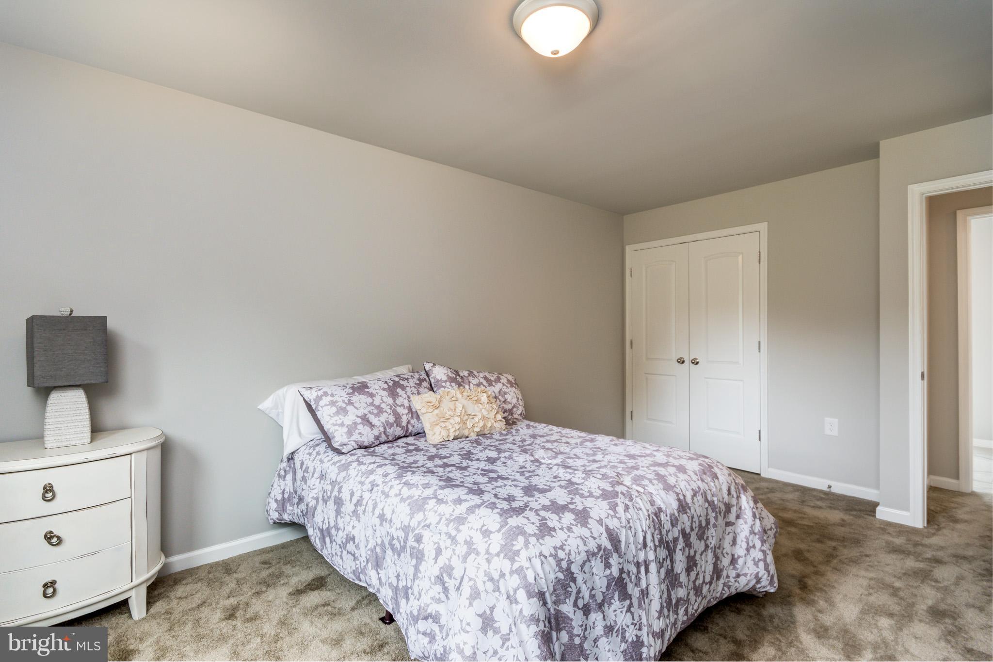 8035 Clark Station Road Severn, MD 21144 - Photo 18 of 24 a bedroom with a bed and a lamp on dresser