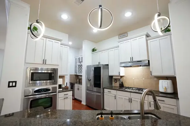 a kitchen with granite countertop a stove a sink and a refrigerator