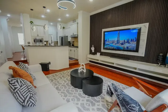 a living room with stainless steel appliances furniture a rug and a view of kitchen