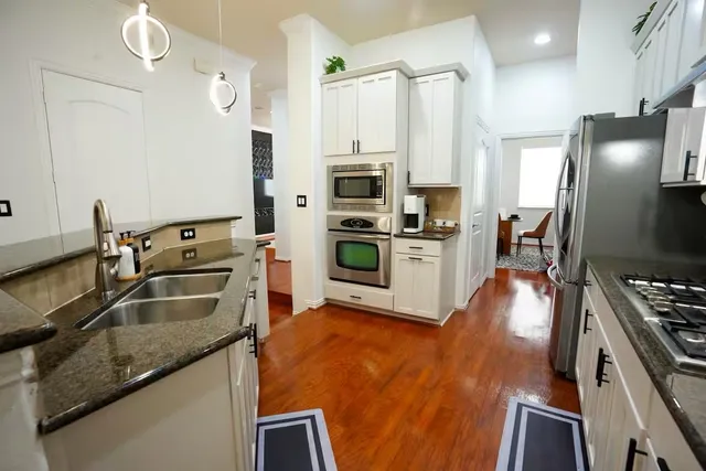 a kitchen with stainless steel appliances granite countertop a refrigerator a stove and a sink