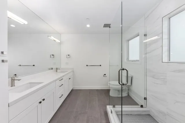 a bathroom with a double vanity sink a toilet and a mirror