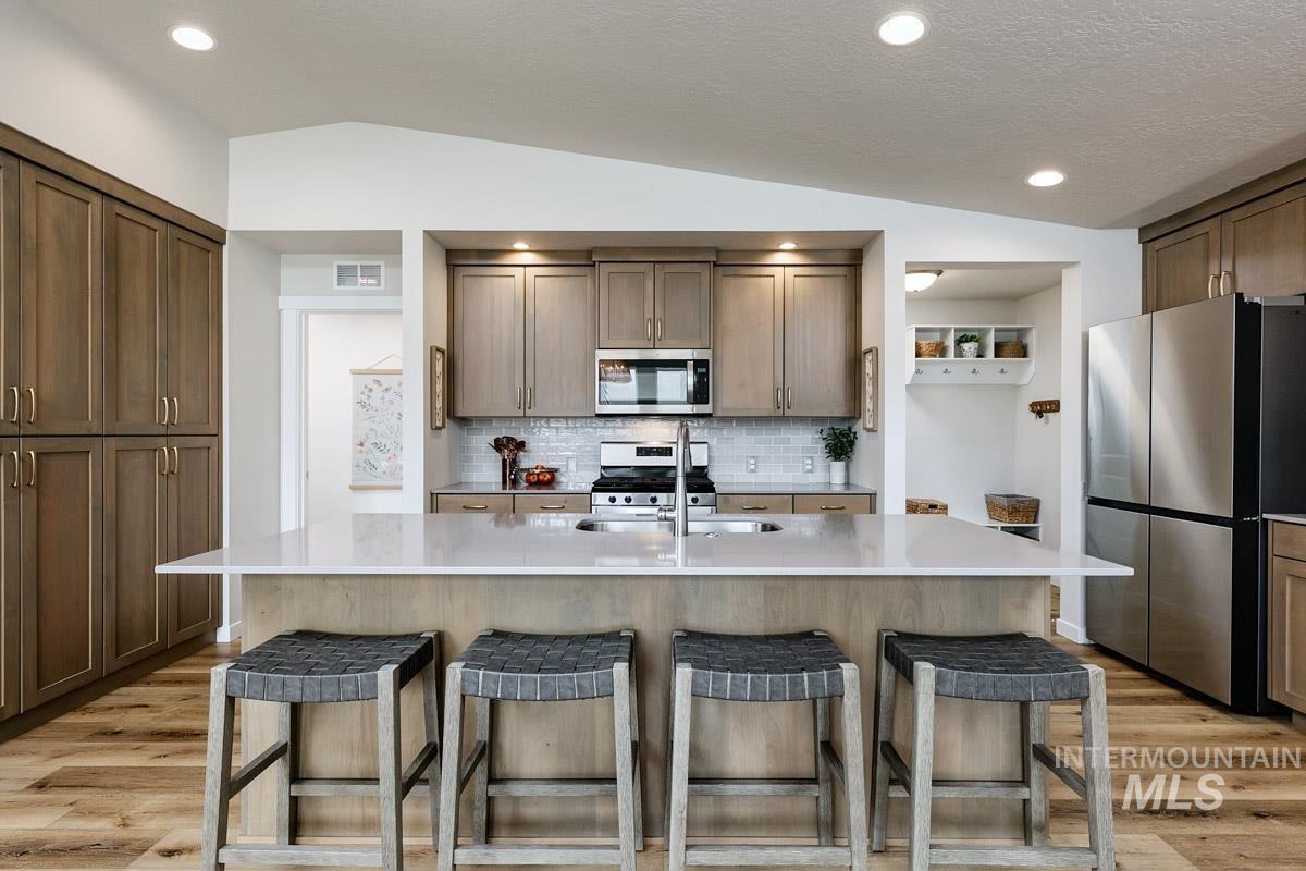 348 West Radiant Rdg Drive Meridian, ID 83642 - Photo 5 of 36 Spacious kitchen featuring a large island with seating, stainless steel appliances, wood-finish flooring, recessed lighting, and extensive cabinetry