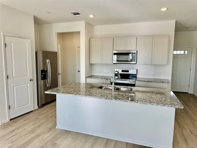 a kitchen with kitchen island granite countertop a refrigerator and a stove top oven