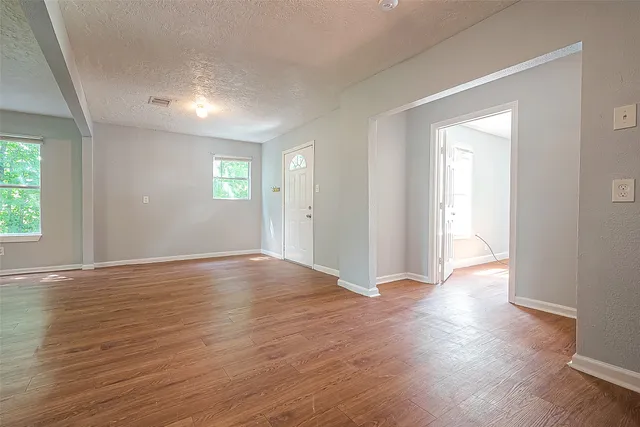 an empty room with wooden floor and windows