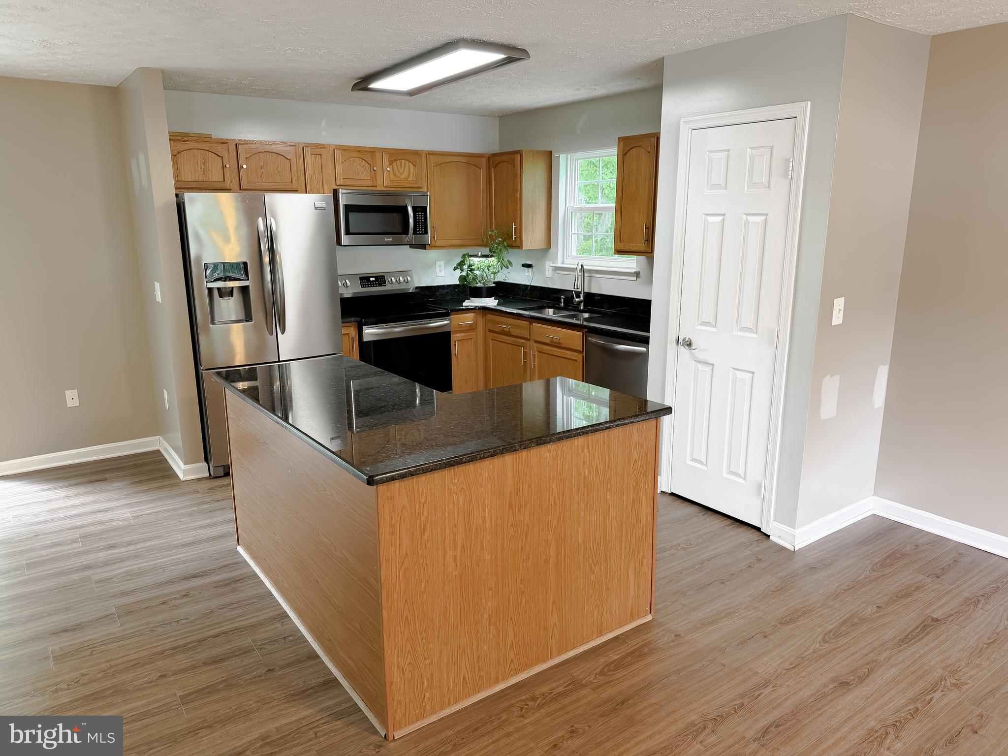 23801 McIntosh Road Hollywood, MD 20636 - Photo 10 of 35 a kitchen with granite countertop a refrigerator and a stove top oven