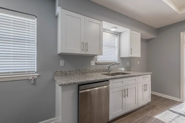 a kitchen with granite countertop cabinets stainless steel appliances a sink and a window