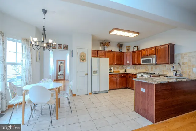 a kitchen with refrigerator a stove a sink dishwasher and a dining table with wooden floor