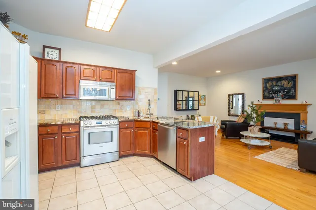 a large kitchen with stainless steel appliances granite countertop a stove top oven a sink dishwasher and cabinets