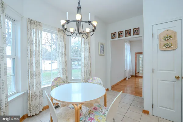 a dining room with wooden floor a chandelier a glass table and chairs