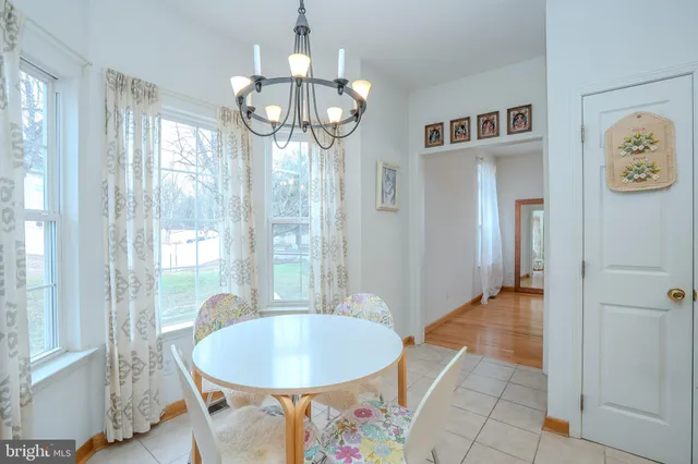 a dining room with wooden floor a chandelier a glass table and chairs