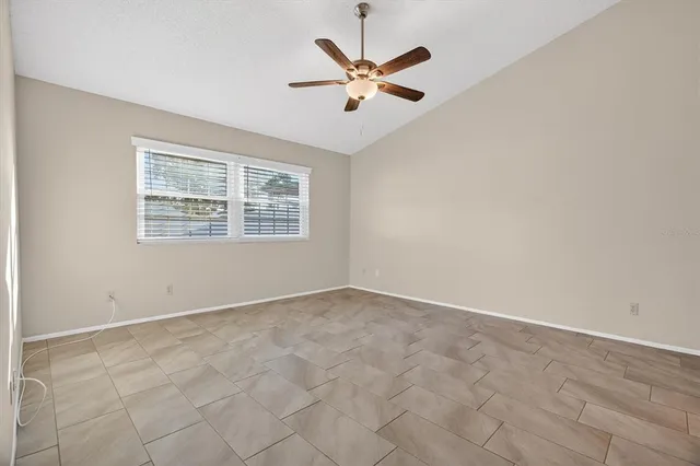 an empty room with ceiling fan and window