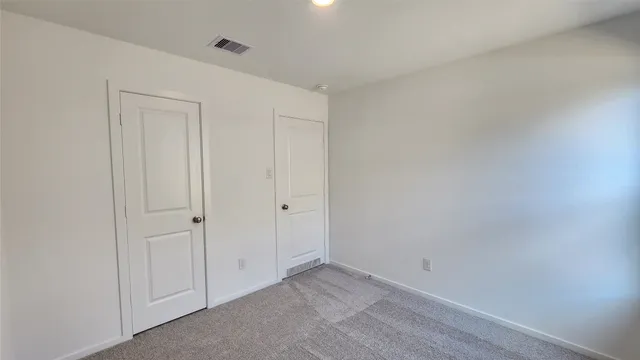 a view of an empty room with a window and closet area