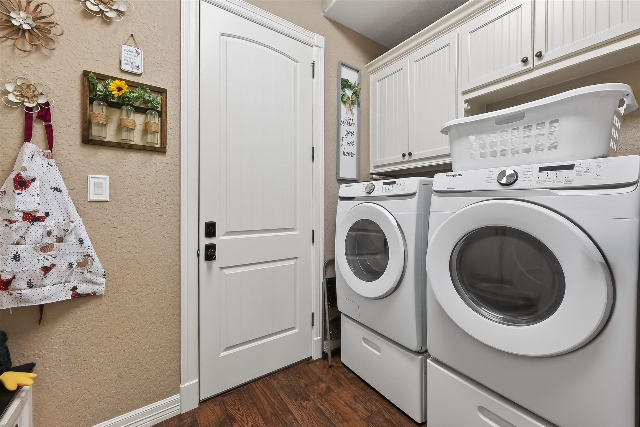 912 County Road 340 Angleton, TX 77515 - Photo 20 of 50 This photo showcases a cozy, well-organized laundry room with white cabinetry for storage. The room has a warm, inviting feel with its wooden flooring and neutral wall color.