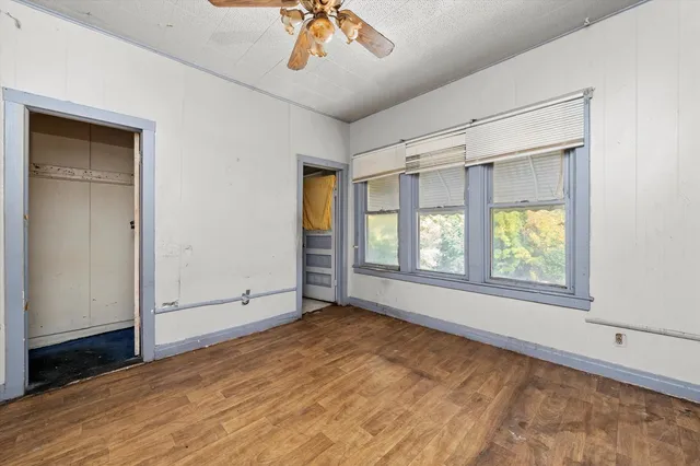 a view of an empty room with a window and wooden floor