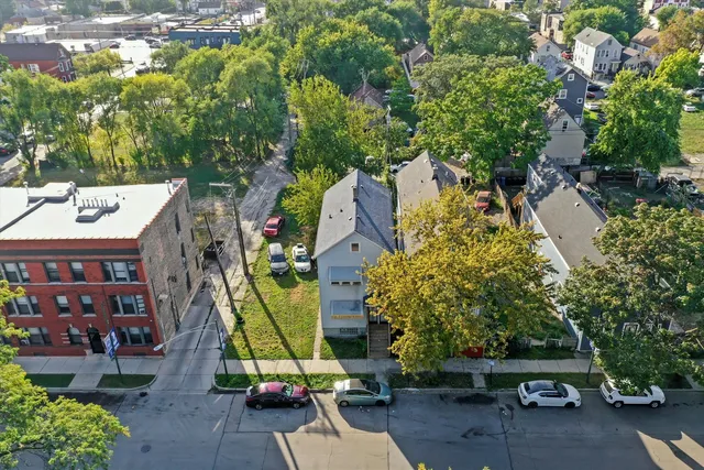 a view of a white house with a big yard and large tree