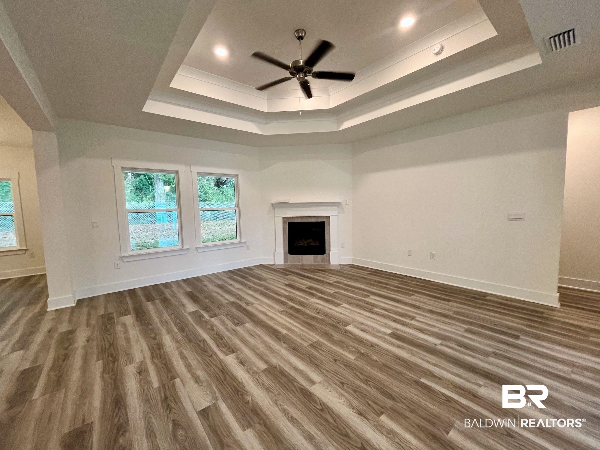 334 Barndling Street Fairhope, AL 36532 - Photo 10 of 34 Unfurnished living room with a tray ceiling, a tile fireplace, and dark hardwood / wood-style floors