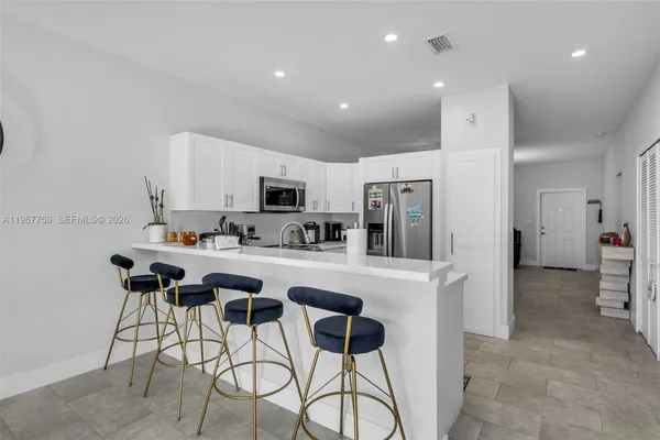 a kitchen with stainless steel appliances kitchen island granite countertop a refrigerator and a stove top oven