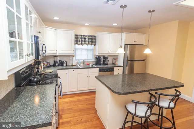 a kitchen with stainless steel appliances granite countertop a sink a stove a refrigerator and island
