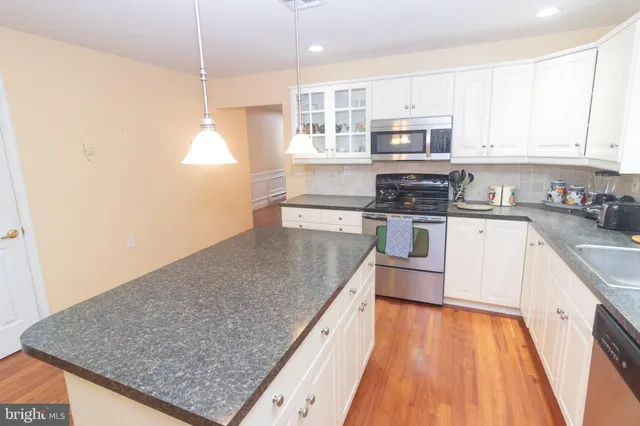 a kitchen with stainless steel appliances granite countertop a sink a stove and a wooden floors