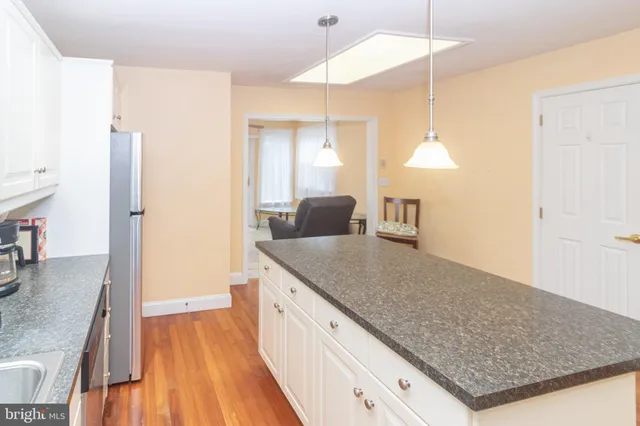 a kitchen with kitchen island a counter top space a sink a refrigerator and wooden floor