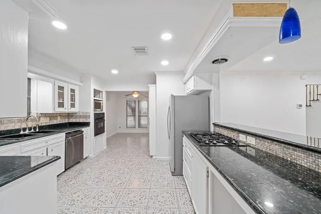 a large kitchen with granite countertop a sink and cabinets