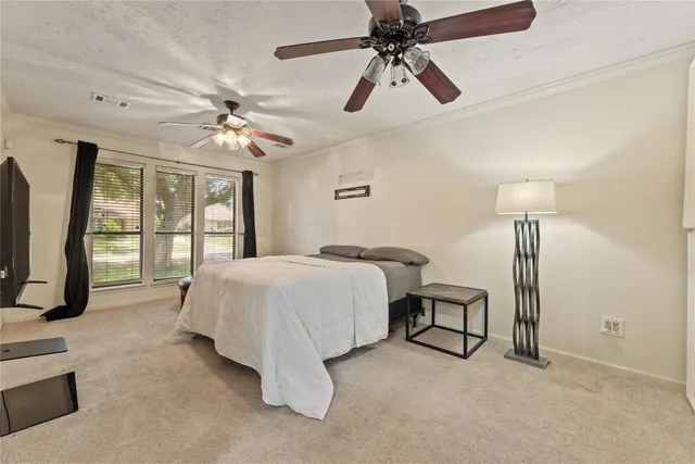 a spacious bedroom with a bed a chandelier and large window