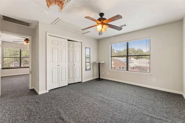 an empty room with windows and chandelier fan