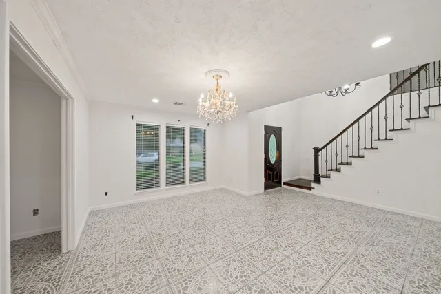 a view of an empty room with wooden floor and stairs