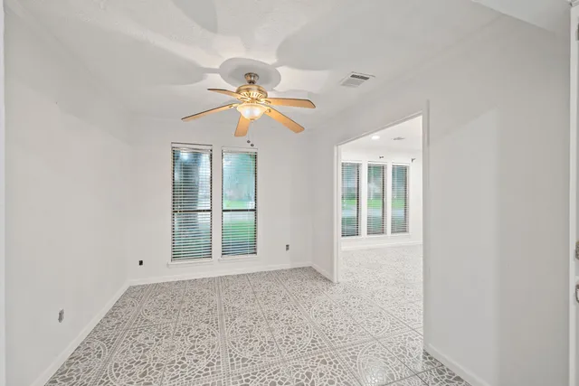 an empty room with windows and fan