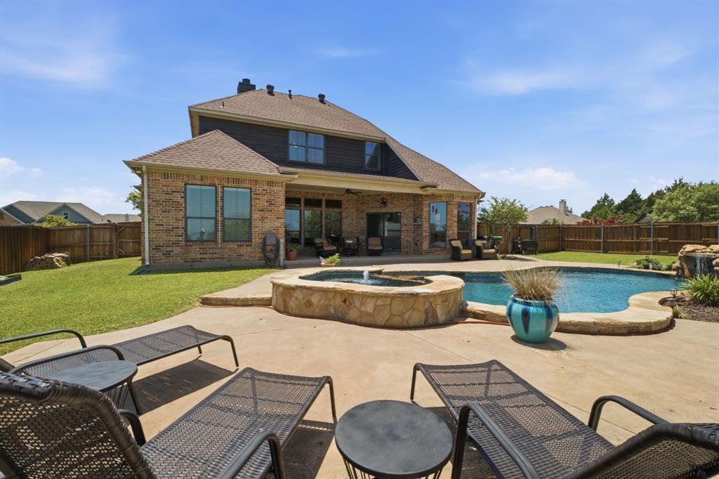 600 Aspen Street Pilot Point, TX 76258 - Photo 31 of 39 Expansive backyard featuring a freeform pool, integrated stone-clad spa with fountain, concrete patio, and a privacy fence