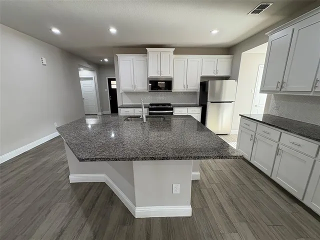 a kitchen with stainless steel appliances granite countertop wooden cabinets a stove a sink and dishwasher