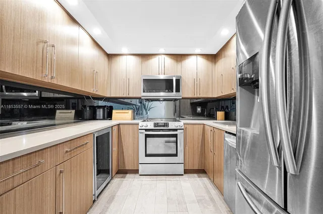 a kitchen with stainless steel appliances granite countertop a refrigerator a stove and a sink with wooden floor