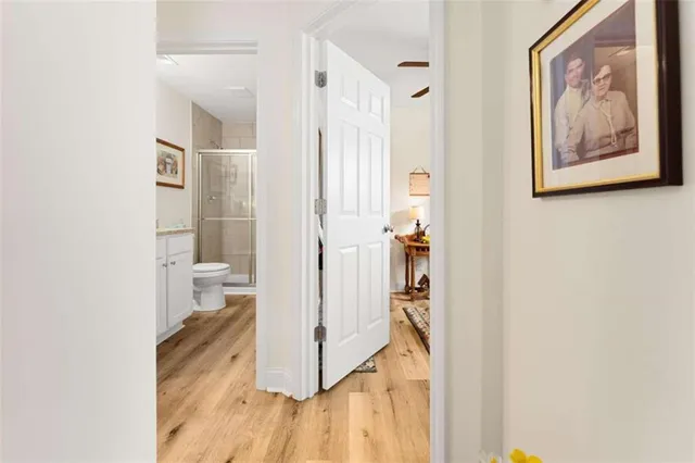 a view of a hallway with wooden floor and a bathroom