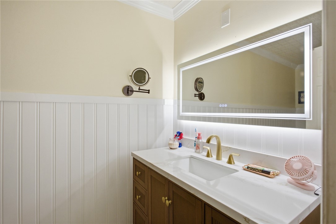 311 Cumberland Way Anderson, SC 29621 - Photo 16 of 44 A sleek vanity with a wide, illuminated mirror and beadboard wainscoting creates a clean, inviting atmosphere.