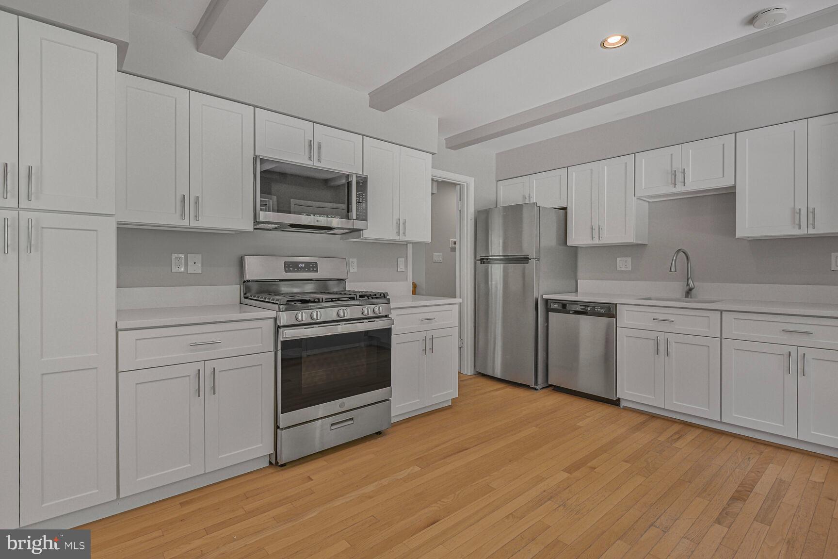 11733 Ambleside Drive Potomac, MD 20854 - Photo 8 of 29 a kitchen with stainless steel appliances white cabinets a sink a stove a microwave and cabinetry