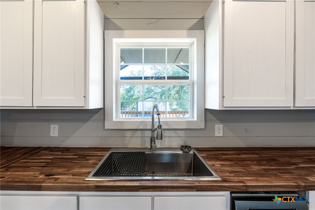 18248 Crows Ranch Road Salado, TX 76571 - Photo 39 of 48 a kitchen with granite countertop a sink and white cabinets