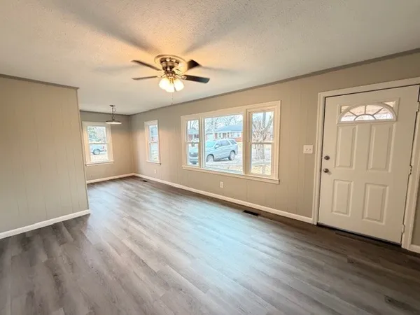 a view of an empty room with a window and wooden floor