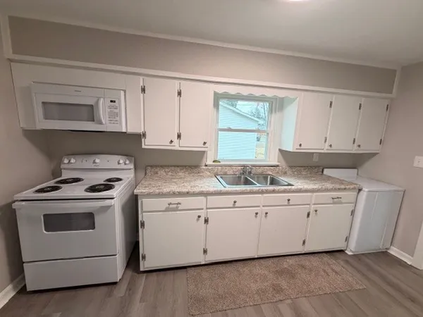 a kitchen with granite countertop white cabinets and white appliances