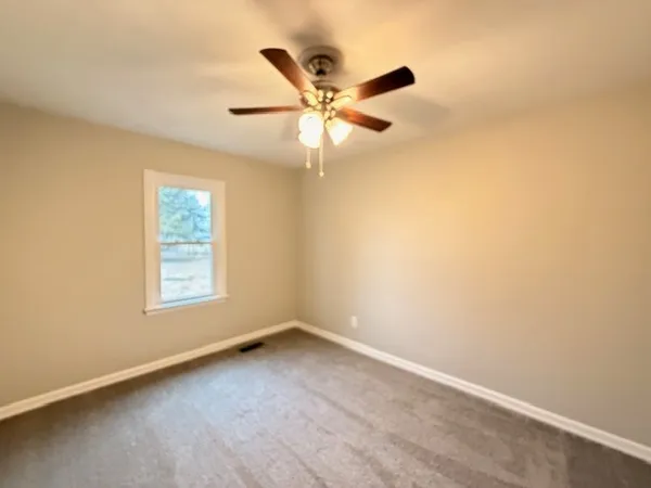 an empty room with a window and a ceiling fan