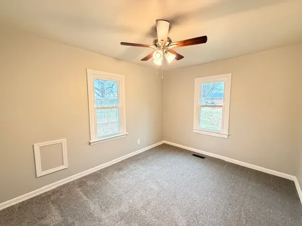an empty room with windows and fan