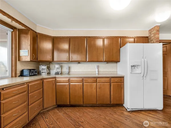 a kitchen with stainless steel appliances granite countertop a refrigerator a sink and wooden cabinets