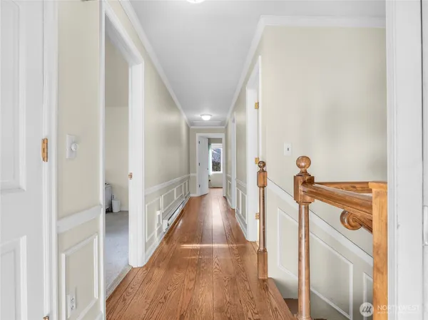 a view of a hallway with wooden floor and a bathroom