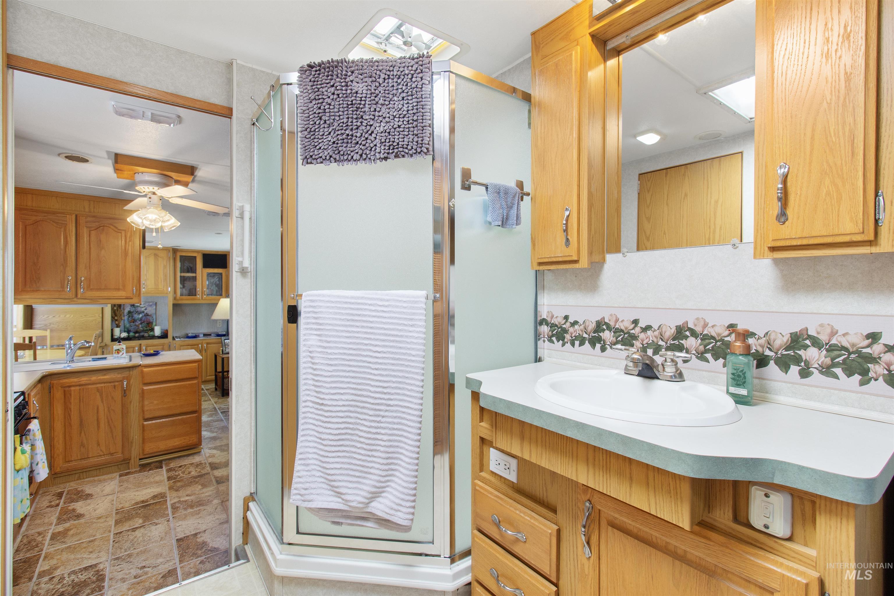 106 West Magic Road Shoshone, ID 83352 - Photo 26 of 45 Bathroom featuring a corner shower enclosure, a vanity with wood-finish cabinetry, an integrated sink, and an overhead mirrored medicine cabinet