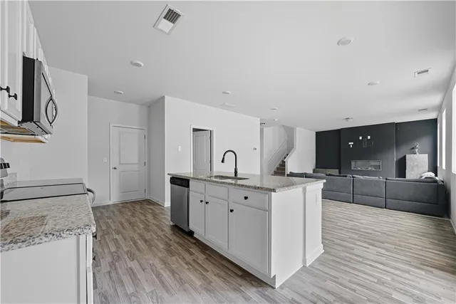 a kitchen with stainless steel appliances granite countertop a sink dishwasher stove and microwave with wooden cabinets