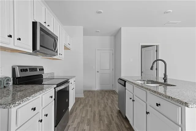 a kitchen with stainless steel appliances granite countertop a sink stove and wooden floor